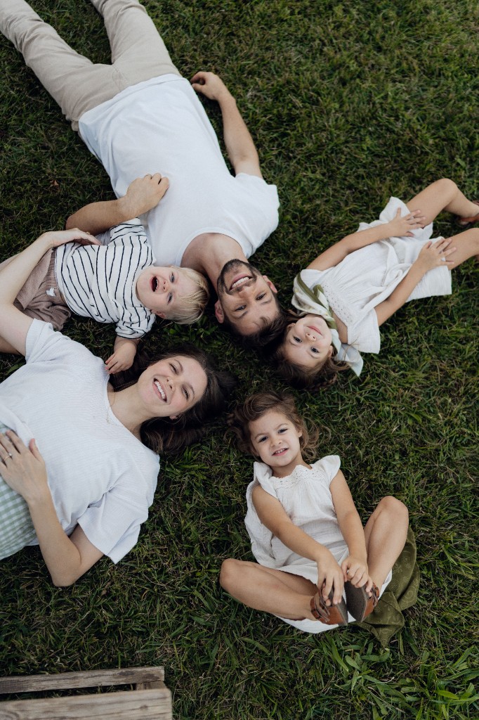 Philipp, Sarah und ihre drei Kinder liegen lachend im Gras