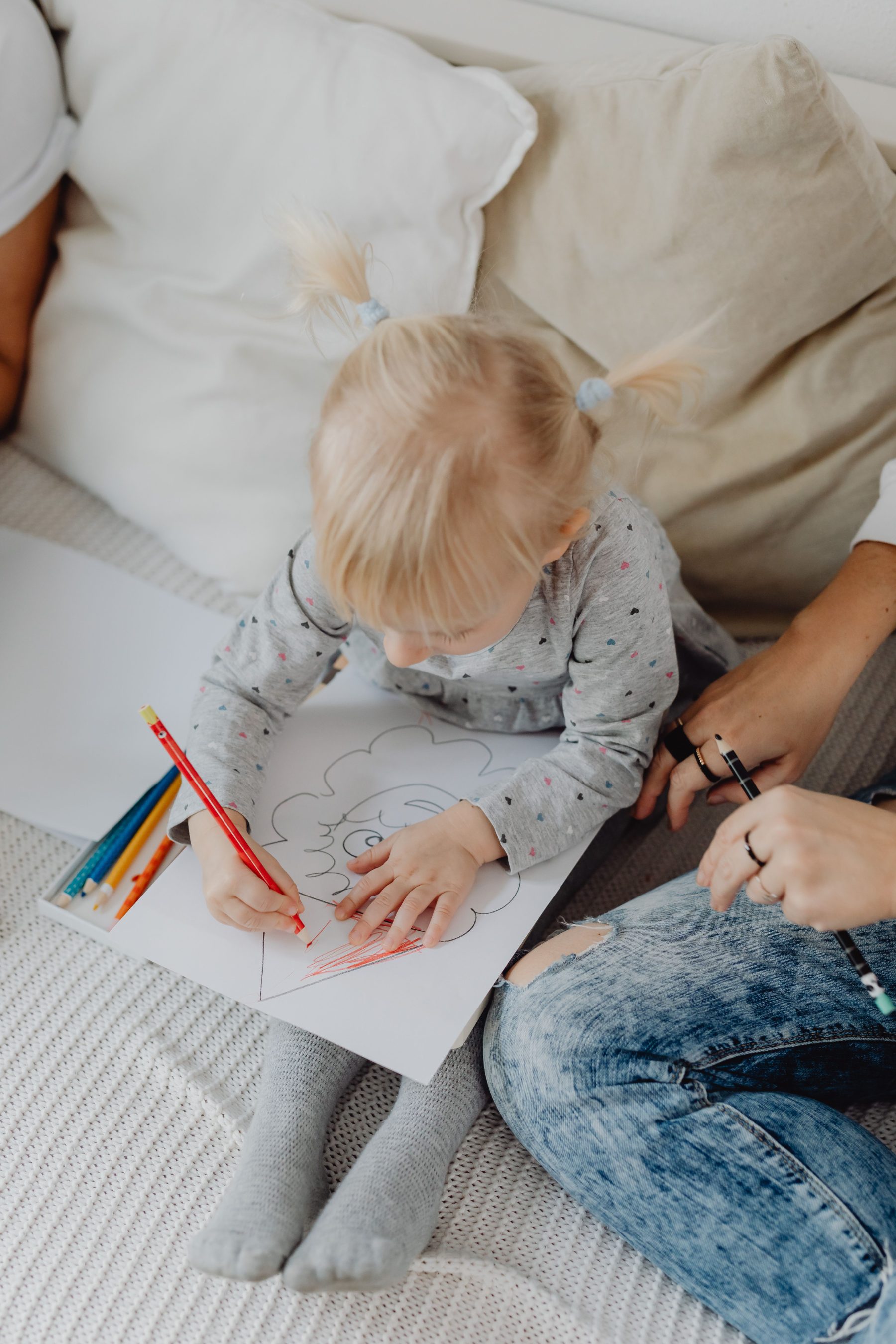 Kind malt mit seiner Mutter auf dem Sofa